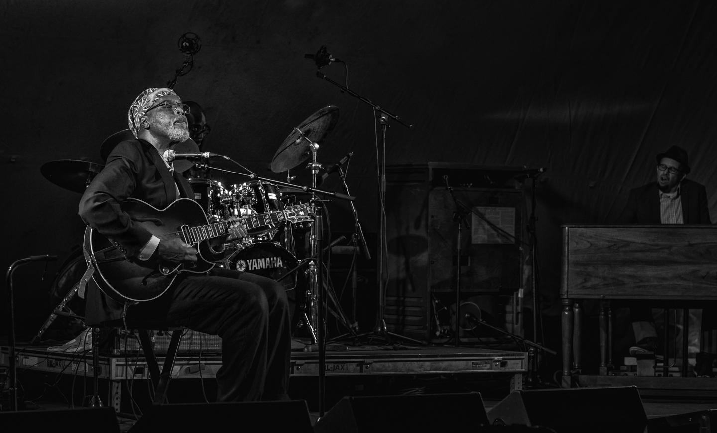 Jazz musician playing guitar on stage, black and white photograph.
