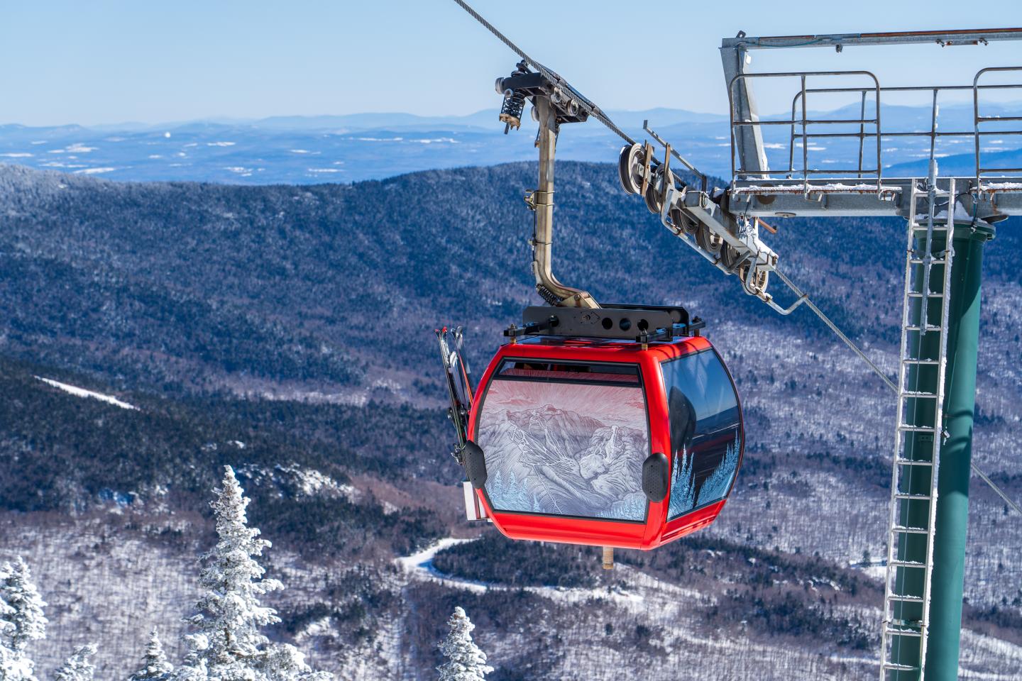 Red gondola lift against snowy mountain backdrop.