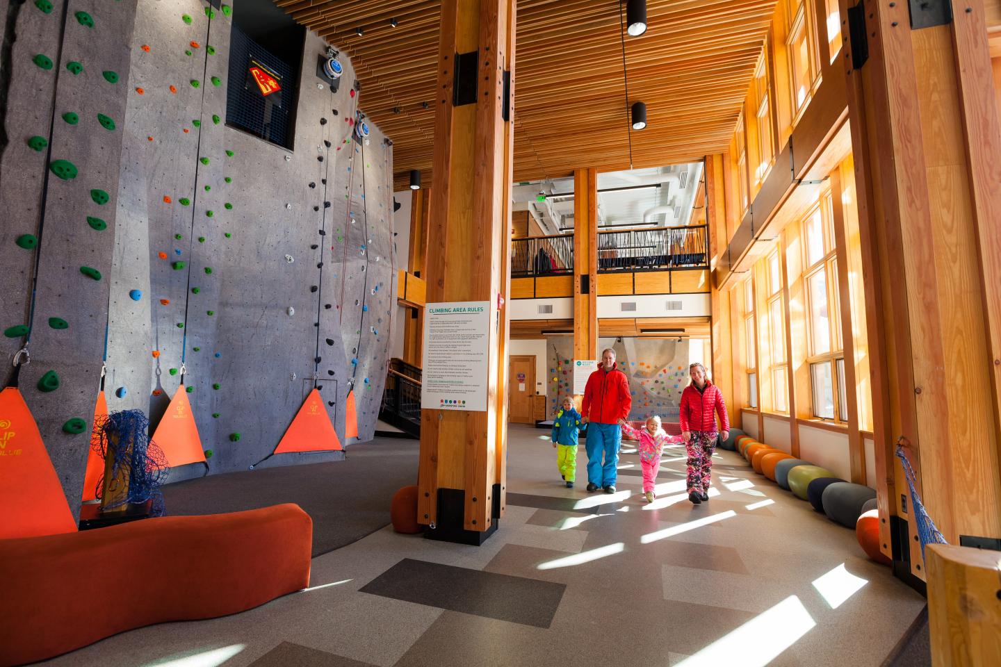 Climbing gym with large windows, a family walks nearby.