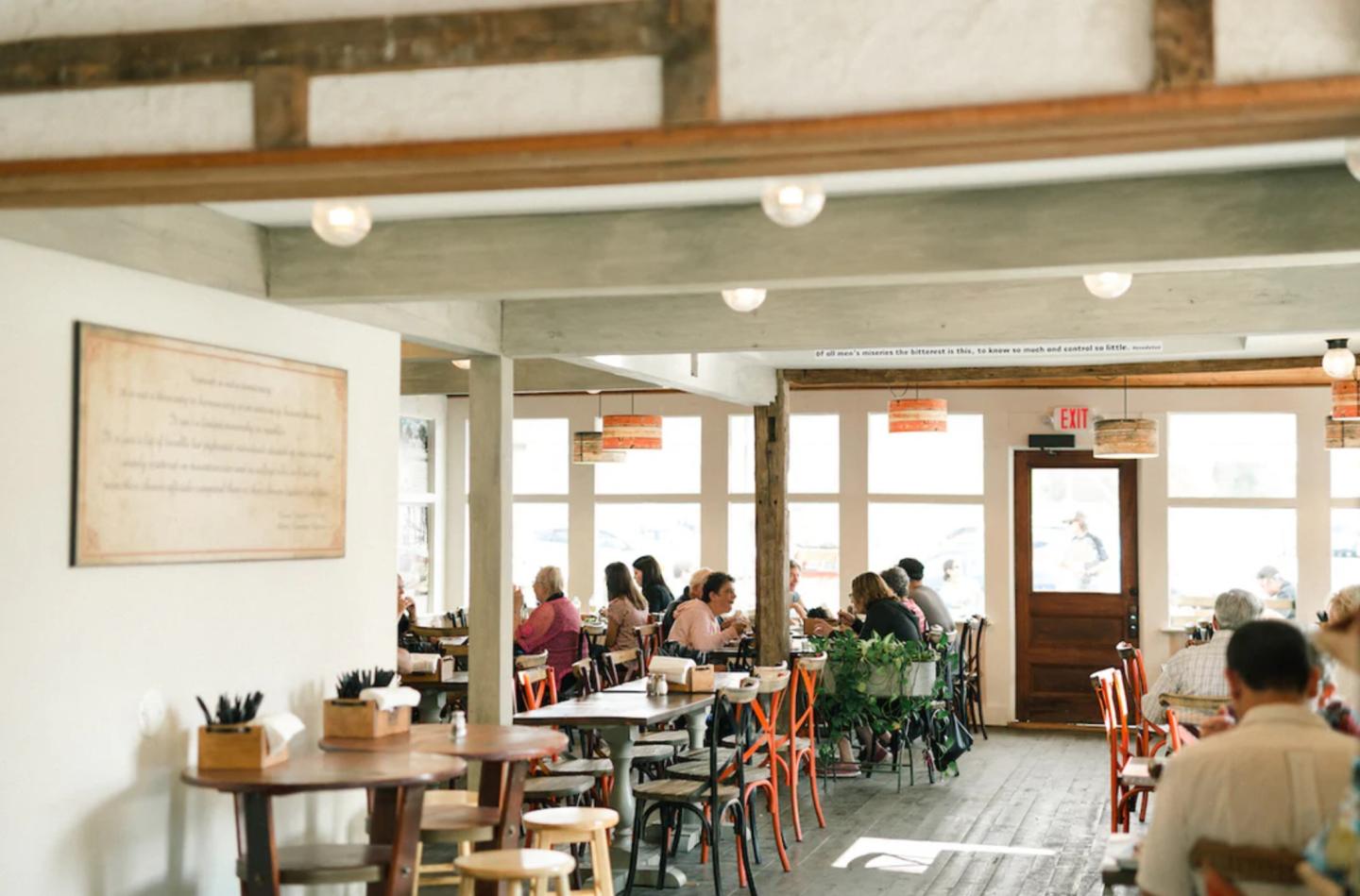 Bright café interior with wooden beams and people dining at tables.